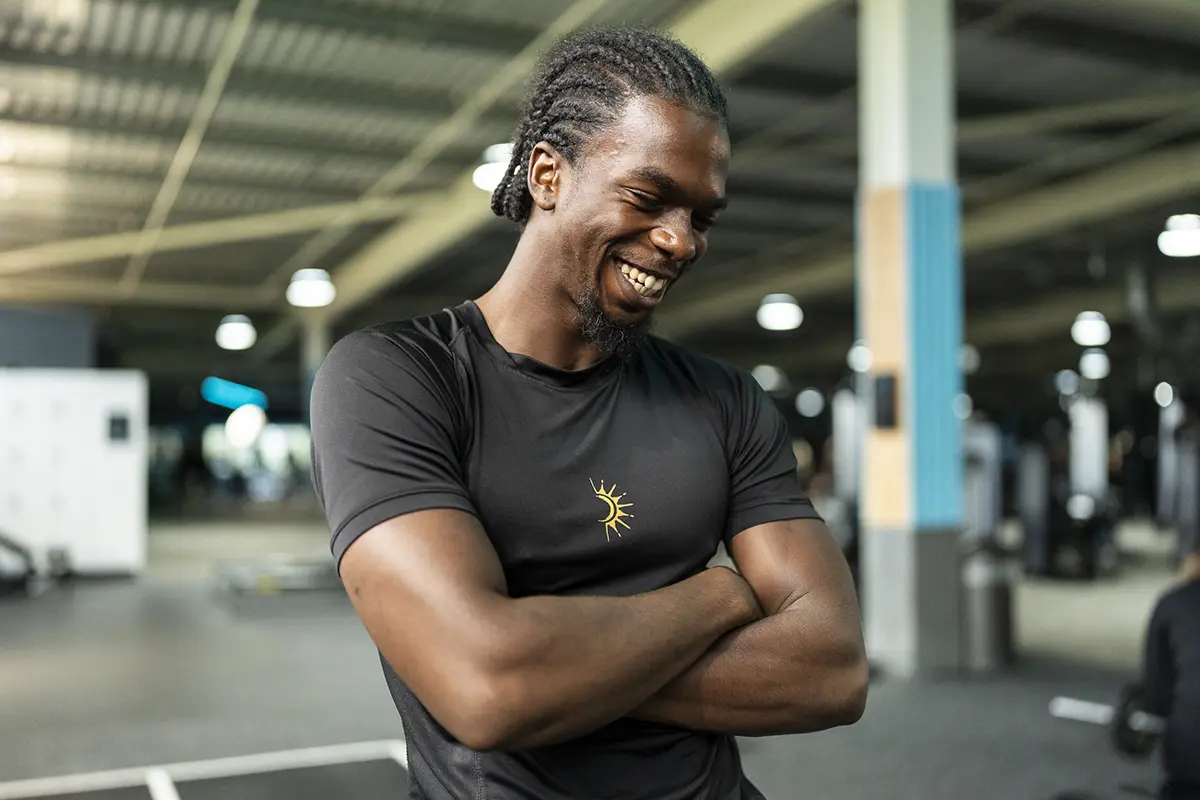 Man smiles with crossed arms as he glances down to the floor