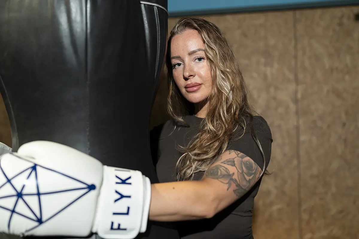 Woman hugs boxing bag and looks to camera